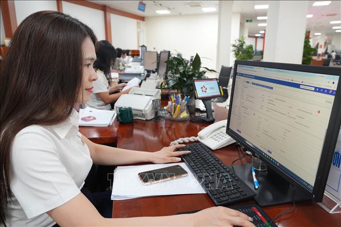 Cán bộ điện lực hoàn thiện hồ sơ cho người dân trên hệ thống trực tuyến tại trung tâm. Ảnh: Tiến Vĩnh – TTXVN 