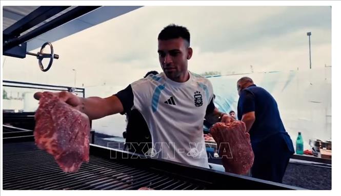 Lautaro Martínez phụ giúp đặt các miếng thịt lên vỉ nướng trong bữa tiệc asado của đội tuyển Argentina. Ảnh: Infobae