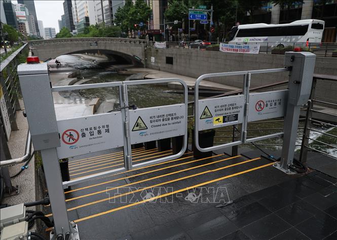 Lối vào tuyến đường đi bộ ven suối Cheonggye ở Seoul (Hàn Quốc) bị đóng cửa do nước tràn bờ sau những trận mưa lớn, ngày 7/7/2026. Ảnh: Yonhap/TTXVN phát