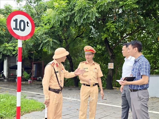 Cán bộ Đội Cảnh sát giao thông đường bộ số 15 (Phòng Cảnh sát giao thông Hà Nội) phối hợp với chính quyền địa phương kiểm tra thực tế hệ thống biển báo hạn chế trọng tải trên đường Lê Hữu Tựu (xã Phúc Thịnh) sau phản ánh của người dân. Ảnh: Trung Nguyên - TTXVN