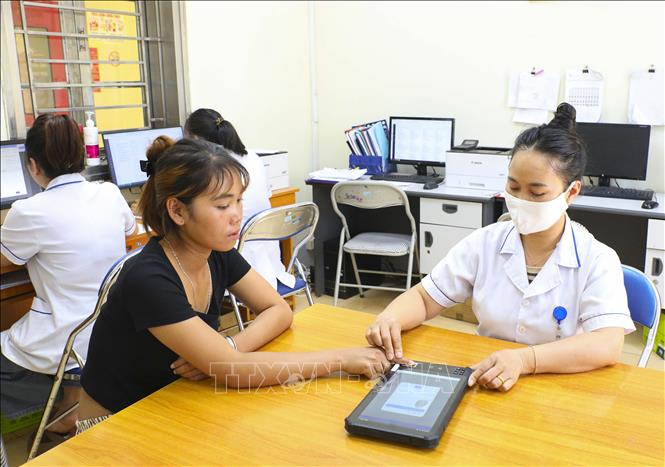 Hướng dẫn bệnh nhân ký sinh trắc học bằng vân tay trên máy tính bảng tại Trung tâm Y tế Thanh An (Điện Biên). Ảnh: Xuân Tư - TTXVN