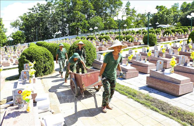 Dưới cái nắng gay gắt, các chiến sĩ Bộ Chỉ huy Quân sự tỉnh Điện Biên phối hợp vận chuyển vật liệu, thực hiện từng công đoạn hoàn trả nguyên trạng phần mộ liệt sĩ một cách tỉ mỉ, cẩn trọng. Ảnh: Xuân Tư - TTXVN