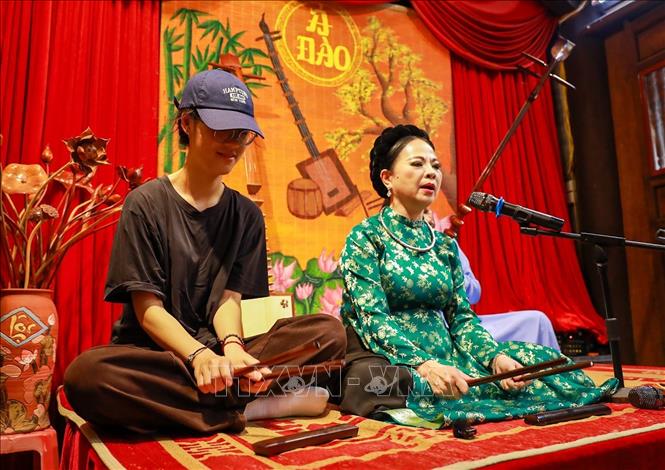 Các bạn trẻ trải nghiệm nghệ thuật ca trù truyến thống. Ảnh: Khánh Hoà - TTXVN

