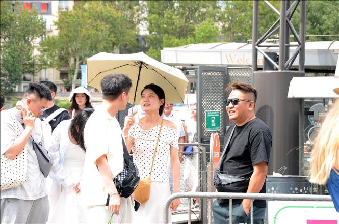 Nhiều du khách sử dụng ô che nắng khi tham quan khu vực ven sông Seine ở thủ đô Paris, ngày 14/7/2026. Ảnh: Hữu Chiến - PV TTXVN tại Pháp