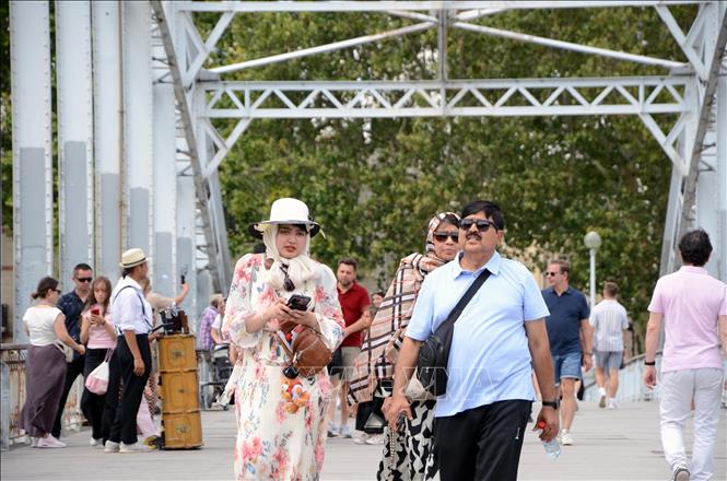 Người dân và du khách đi bộ trên cầu bắc qua sông Seine trong thời tiết nắng nóng tại thủ đô Paris (Pháp), ngày 14/7/2026. Ảnh: Hữu Chiến - PV TTXVN tại Pháp