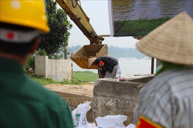 Lực lượng xung kích kiểm tra, cố định móc xích trước khi nâng tấm phai bê tông. Ảnh: Trung Nguyên - TTXVN