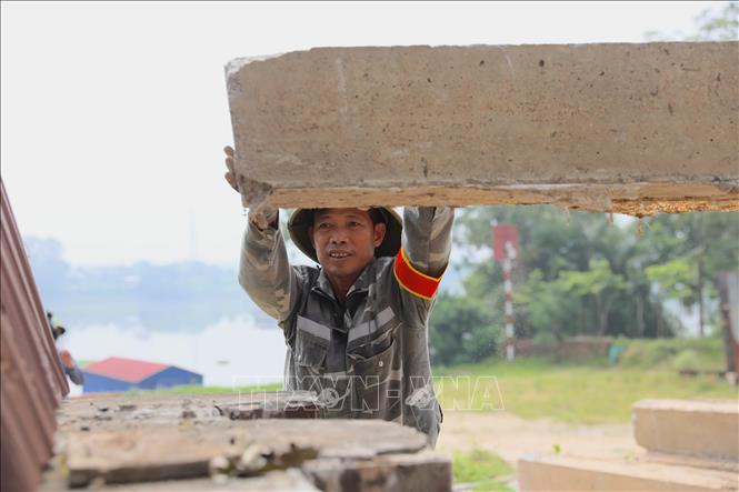 Thành viên lực lượng xung kích giữ ổn định tấm phai trong quá trình thực hành đóng cửa khẩu đê. Ảnh: Trung Nguyên - TTXVN