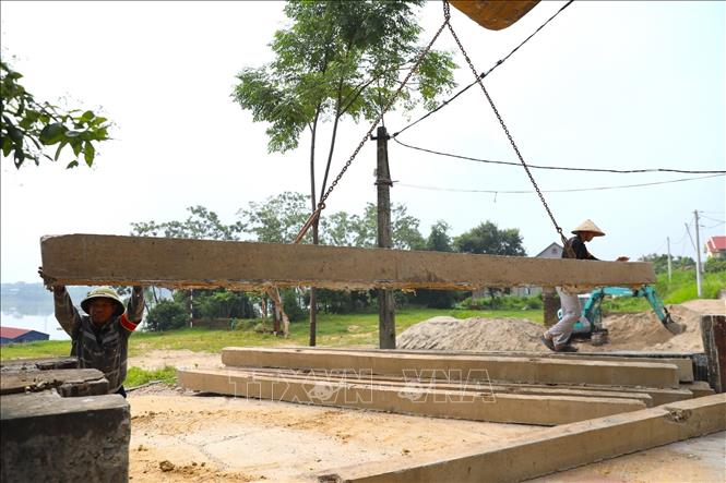 Thành viên lực lượng xung kích giữ ổn định tấm phai trong quá trình thực hành đóng cửa khẩu đê. Ảnh: Trung Nguyên - TTXVN