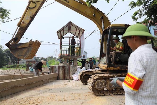 Tấm phai bê tông được phương tiện cơ giới nâng khỏi vị trí tập kết để đưa tới khe cửa khẩu đê Đô Tân. Ảnh: Trung Nguyên - TTXVN