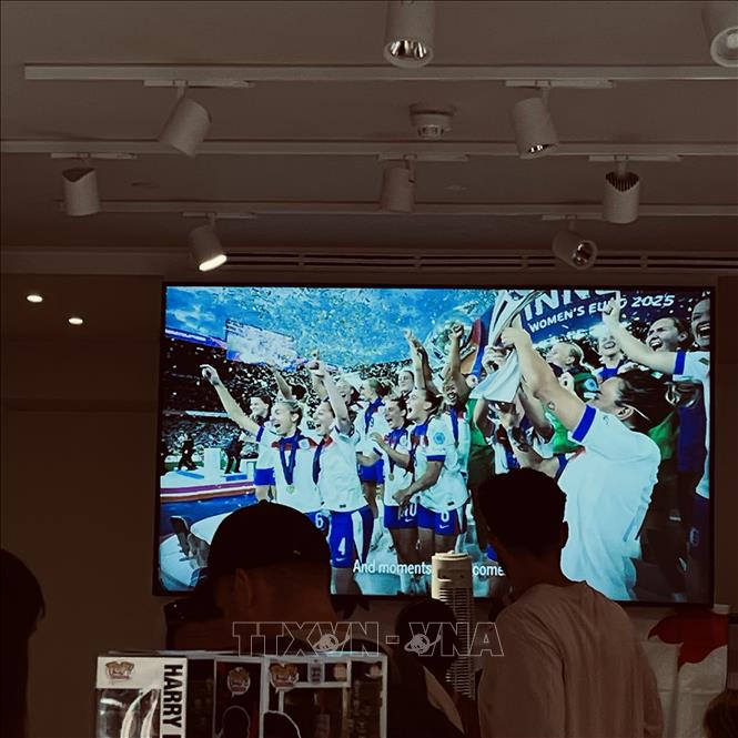 Màn hình trong cửa hàng chính thức của đội tuyển Anh phát lại khoảnh khắc đội tuyển nữ đăng quang EURO 2025, trong bầu không khí chờ đợi trận bán kết World Cup giữa Anh với Argentina. Ảnh: Hương Giang - PV TTXVN tại Anh