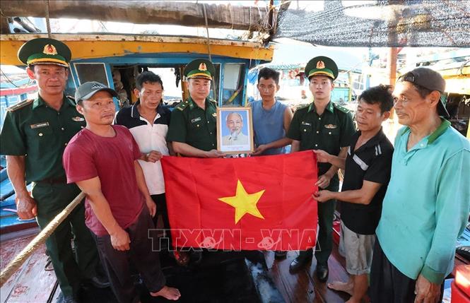 BĐBP cửa khẩu cảng Cửa Sót tặng cờ Tổ quốc cho ngư dân trước khi ra khơi khai thác thuỷ sản. Ảnh: Vũ Sinh - TTXVN