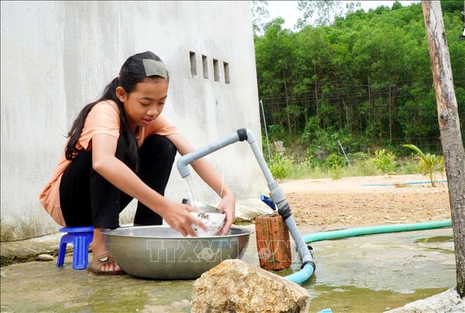 Người dân vui mừng khi được sử dụng nước sạch tại khu tái định cư. Ảnh: Lê Phước Ngọc - TTXVN