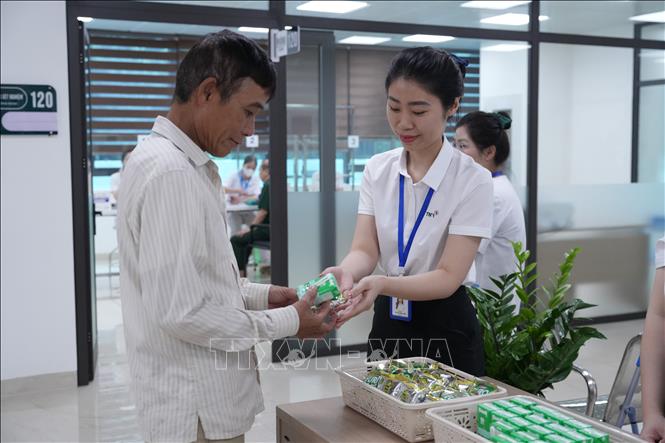 Cấp phát thuốc và sữa miễn phí cho người có công với cách mạng. Ảnh: Tiến Vĩnh –TTXVN 