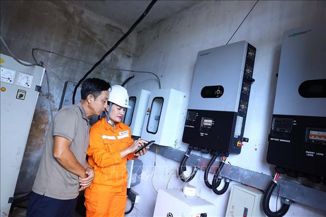 Nhân viên công ty điện lực Hà Tĩnh hướng dẫn người dân sử dụng điện từ nguồn điện mặt trời an toàn, hiệu quả. Ảnh: Huy Hùng - TTXVN