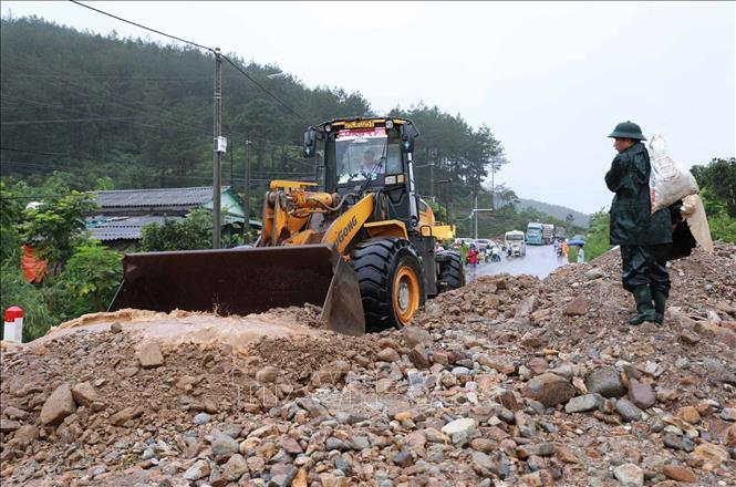Lực lượng chức năng huy động phương tiện máy móc khắc phục hót sạt sụt trên Quốc lộ 32 sau khi cơn lũ đi qua. Ảnh: Quý Trung - TTXVN