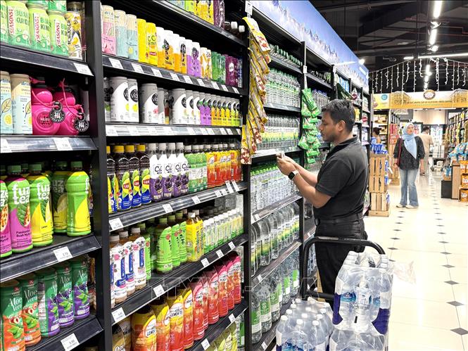 Nhân viên thay đổi giá mặt hàng nước đóng chai tại siêu thị ở Kuala Lumpur, Malaysia. Ảnh: Thanh Bình – PV TTXVN tại Malaysia