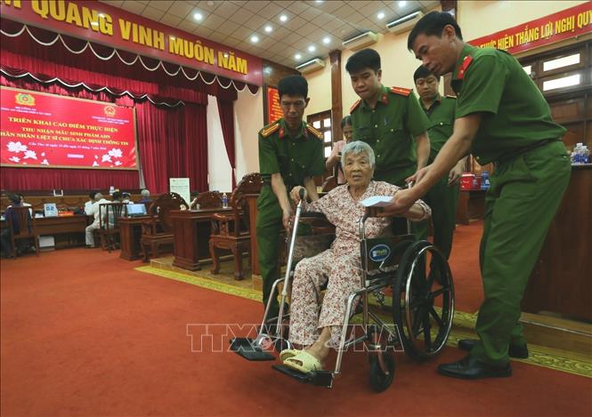 Thân nhân liệt sĩ tuổi cao sức yếu được các chiến sĩ hỗ trợ đưa đón đến điểm lấy mẫu ADN. Ảnh: Duy Khương - TTXVN
