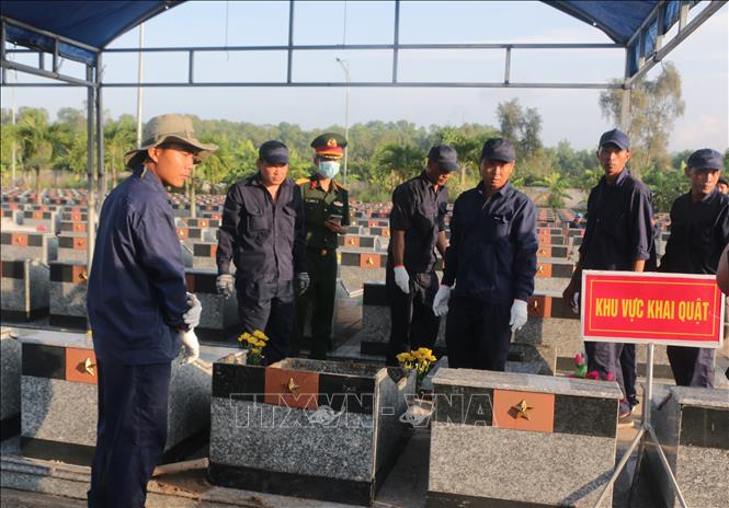 Các lực lượng chức năng tiến hành khai quật mộ để xác định danh tính hài cốt liệt sĩ. Ảnh: Tuấn Kiệt – TTXVN.