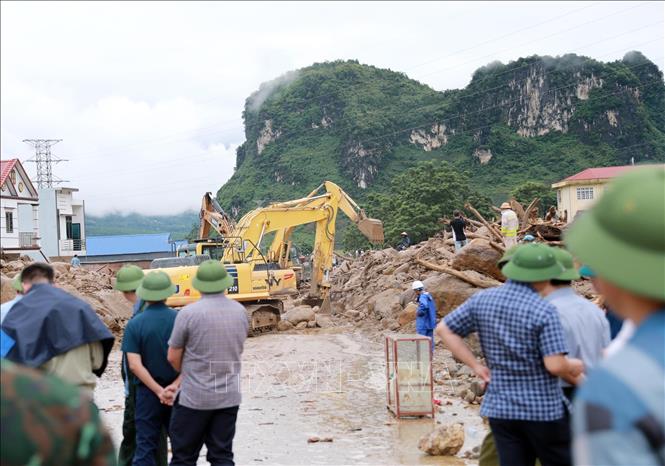 Các phương tiện máy móc tập trung san gạt cây cối, đất đá góp phần thông đường tạm thời cho nhân dân đi lại. Ảnh: Quý Trung - TTXVN