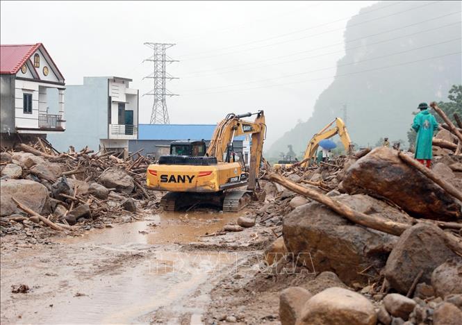 Các phương tiện máy móc tập trung san gạt cây cối, đất đá góp phần thông đường tạm thời cho nhân dân đi lại. Ảnh: Quý Trung - TTXVN