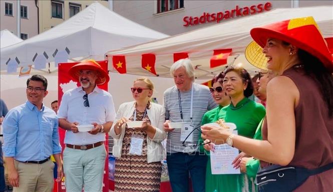 Ông Martin Schenkelberg (đội nón), Trưởng Ban Hội nhập và Xã hội thành phố Augsburg tham quan gian hàng Việt Nam. Ảnh: TTXVN phát