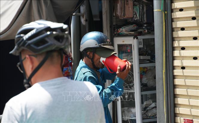 Tiếp nước cho cơ thể khi làm việc ngoài trời nắng nóng gay gắt ở chợ Đông Ba, phường Phú Xuân, thành phố Huế. Ảnh: Nguyên Lý - TTXVN