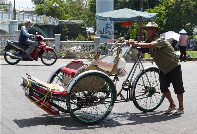 Nhọc nhằn đẩy xe xích lô lên dốc giữa nắng nóng gay gắt ở gần cầu Gia Hội, phường Phú Xuân, thành phố Huế. Ảnh: Nguyên Lý - TTXVN