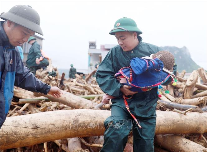  Lực lượng dân quân tựu vệ đưa trẻ em ra khỏi nơi nguy hiểm tại khu vực xảy ra lũ quét xã Mường Than, tỉnh Lai Châu. Ảnh: Quý Trung – TTXVN