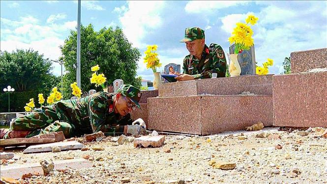 Trung tá Nguyễn Văn Ngọc (trái) trực tiếp đo kích thước từng phần mộ để phục vụ công tác hoàn nguyên. Ảnh: TTXVN phát