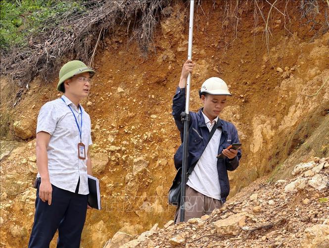  Cán bộ UBND xã Sóc Sơn và đơn vị chuyên môn khảo sát, đo đạc hiện trạng mái dốc để phục vụ việc lập phương án xử lý sự cố sạt trượt. Ảnh: Quốc Luỹ - TTXVN
