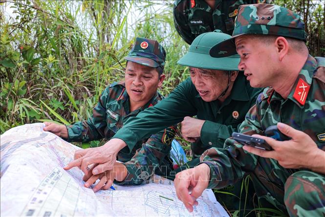 Thành viên đội tìm kiếm, quy tập liệt sĩ cùng cựu chiến binh Dương Việt Hồng đối chiếu thực địa với vị trí nơi chiến địa xưa trên bản đồ. Ảnh: Hoàng Hiếu - TTXVN