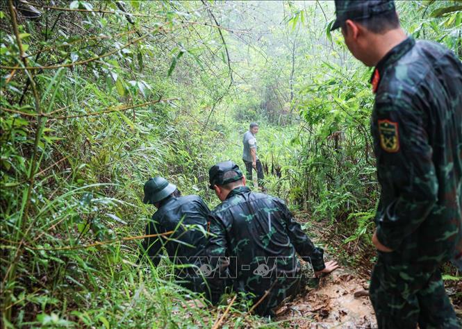 Thành viên đoàn vẫn di chuyển tìm kiếm vị trí hầm sập nghi có liệt sĩ trong điều kiện thời tiết không thuận lợi. Ảnh: Hoàng Hiếu - TTXVN