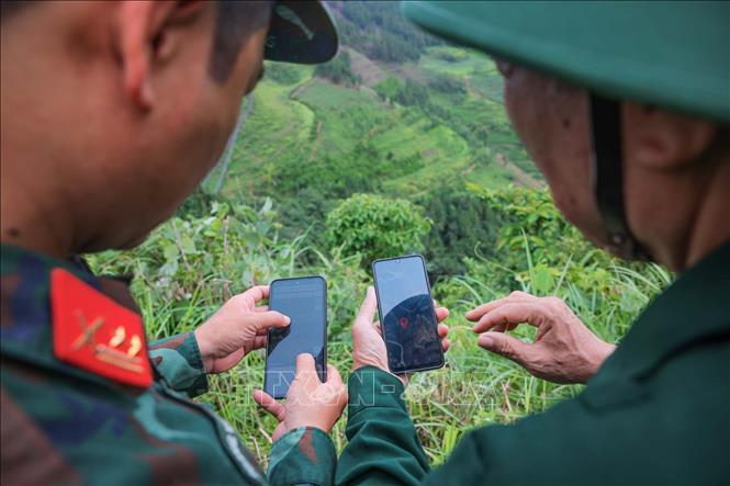 Đồng chí Trung tá Hoàng Vũ Dũng - Phó đội trưởng Đội tìm kiếm, quy tập hài cốt liệt sĩ Bộ CHQS tỉnh Tuyên Quang so sánh thông tin trên bản đồ về vị trí liệt sĩ hy sinh tại xã Bách Đích được cựu chiến binh Dương Việt Hồng cung cấp. Ảnh: Hoàng Hiếu - TTXVN