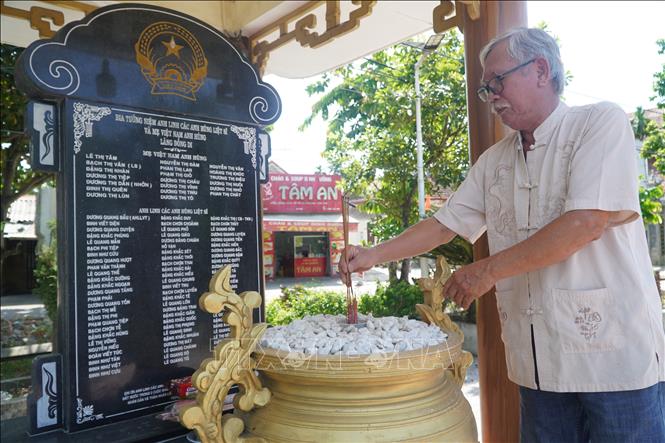 Ông Đặng Quốc Sim (làng Đồng Di, xã Phú Hồ) thắp hương tại Bia tưởng niệm ghi danh các Mẹ Việt Nam anh hùng và Anh hùng liệt sĩ của làng. Ảnh: Mai Trang- TTXVN 