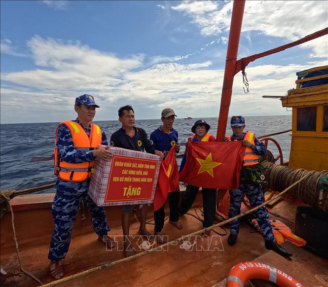 Cán bộ, chiến sĩ Bộ Tư lệnh Vùng Cảnh sát biển 2 trao cờ Tổ quốc và quà động viên ngư dân yên tâm vươn khơi, bám biển, chấp hành đúng các quy định trong khai thác thủy sản. Ảnh: Xuân Quý - TTXVN