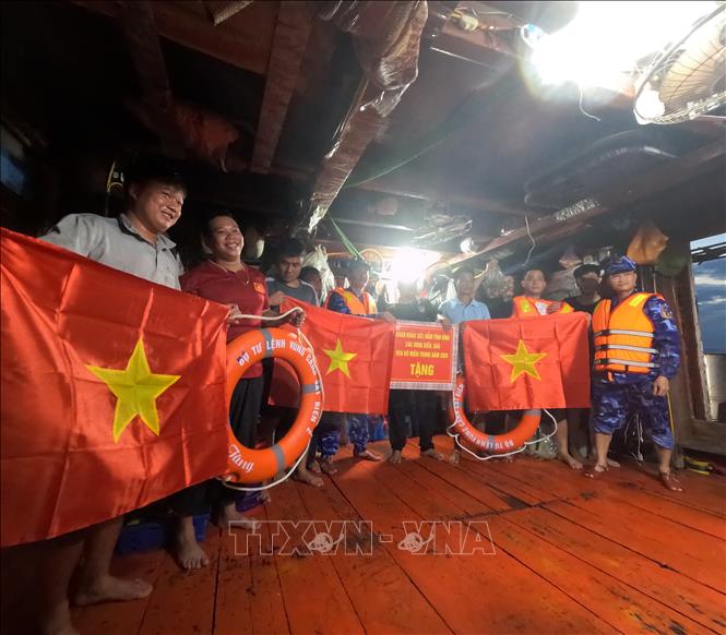 Cán bộ, chiến sĩ Bộ Tư lệnh Vùng Cảnh sát biển 2 trao cờ Tổ quốc và quà động viên ngư dân yên tâm vươn khơi, bám biển, chấp hành đúng các quy định trong khai thác thủy sản. Ảnh: Xuân Quý - TTXVN