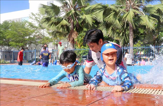 Các chiến sĩ trong Đội chữa cháy và cứu nạn cứu hộ khu vực Mỹ Thới hướng dẫn học sinh kỹ năng dùng chân trong khi bơi. Ảnh: Công Mạo - TTXVN
