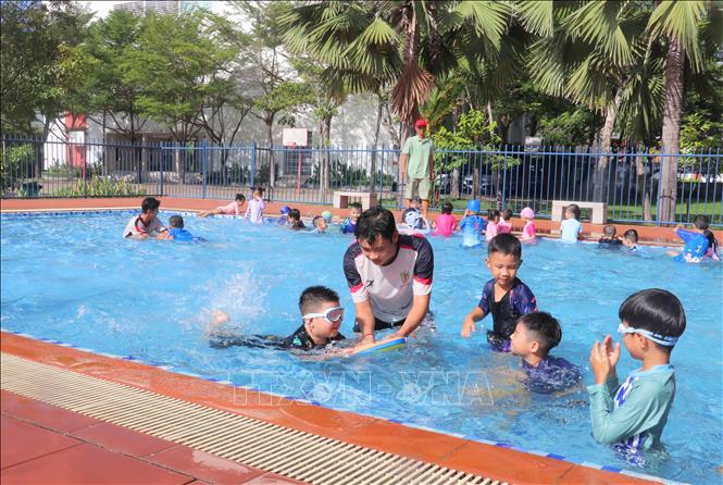 Các chiến sĩ trong Đội chữa cháy và cứu nạn cứu hộ khu vực Mỹ Thới tận tình hướng dẫn học sinh kỹ năng giữ thăng bằng và nổi trên mặt nước khi bơi. Ảnh: Công Mạo - TTXVN