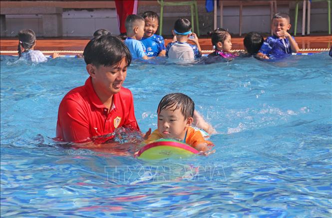 Các chiến sĩ trong Đội chữa cháy và cứu nạn cứu hộ khu vực Mỹ Thới (thuộc Phòng Cảnh sát Phòng cháy chữa cháy và cứu nạn cứu hộ Công an tỉnh An Giang) tận tình hướng dẫn học sinh nhỏ kỹ năng giữ thăng bằng và nổi trên mặt nước khi bơi. Ảnh: Công Mạo - TTXVN