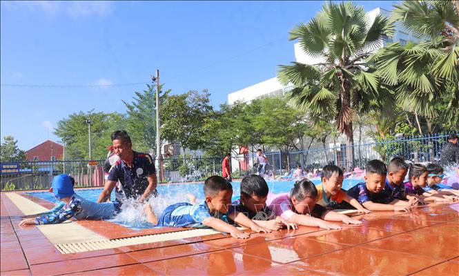Các chiến sĩ trong Đội chữa cháy và cứu nạn cứu hộ khu vực Mỹ Thới hướng dẫn học sinh kỹ năng dùng chân trong khi bơi. Ảnh: Công Mạo - TTXVN