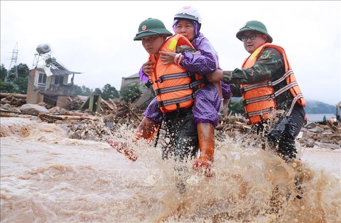 Chiến sĩ quân đội đưa người dân ra khỏi nơi nguy hiểm tại khu vực xảy ra lũ quét xã Mường Than. Ảnh: Quý Trung – TTXVN