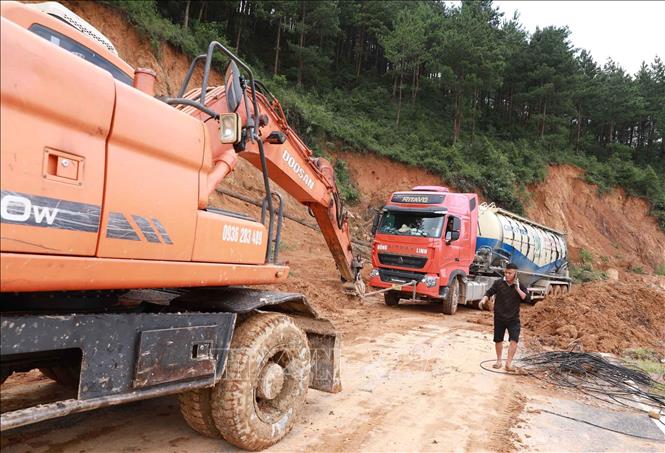 Một xe có tải trọng lớn cần sự hỗ trợ xe kéo khi đi vào đoạn sạt lở trên quốc lộ 279. Ảnh: Quý Trung - TTXVN