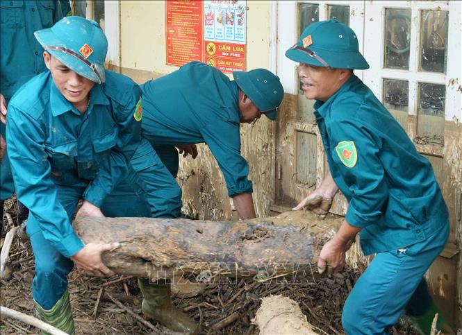 Dân quân tự vệ tỉnh Lai Châu dọn đẹp củi, rác sau lũ dữ ở Mường Than. Ảnh: Nguyễn Oanh-TTXVN.