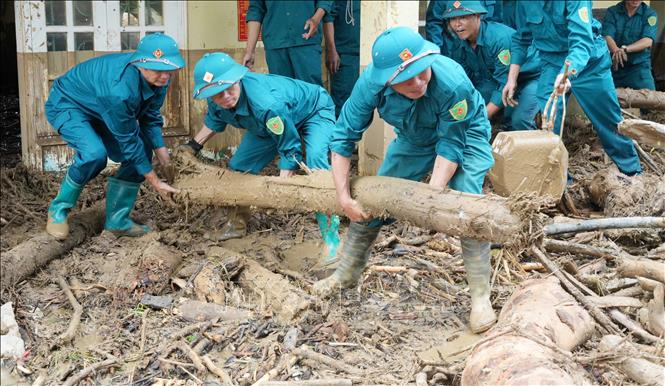 Dân quân tự vệ tỉnh Lai Châu dọn đẹp củi, rác sau lũ dữ ở Mường Than. Ảnh: Nguyễn Oanh-TTXVN.
