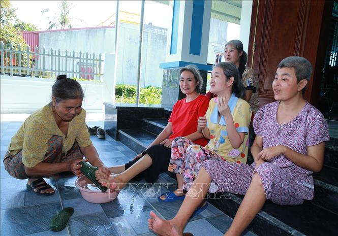 Bà Nguyễn Thị Đàn, xã Quảng Trung (Thanh Hóa) đang chăm sóc bốn đứa con gái bị ảnh hưởng chất độc da cam từ chồng là bệnh binh Lê Đình Dểnh. Ảnh: Trọng Đức - TTXVN