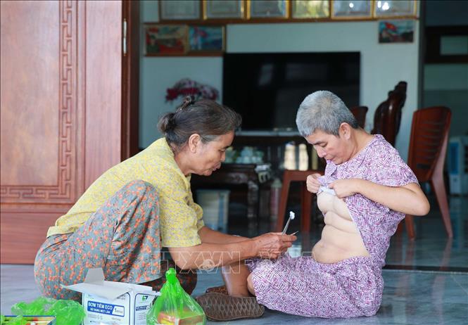 Bà Nguyễn Thị Đàn, xã Quảng Trung (Thanh Hóa) đang chăm sóc một trong bốn đứa con gái bị ảnh hưởng chất độc da cam từ chồng là bệnh binh Lê Đình Dểnh. Ảnh: Trọng Đức - TTXVN