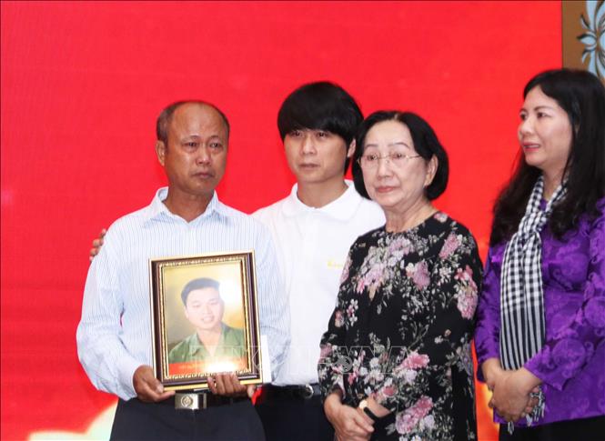 Trưởng nhóm phục dựng ảnh Team Lee, anh Lê Quyết Thắng (thứ hai, từ trái sang) trao di ảnh cho thân nhân liệt sĩ Nguyễn Xuân Thạnh. Ảnh: Xuân Khu-TTXVN