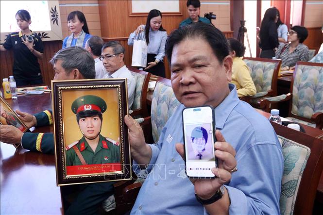 Ông Nguyễn Văn Hoàng bên tấm di ảnh anh trai được phục dựng từ một tấm ảnh thẻ học sinh. Ảnh: Xuân Khu - TTXVN