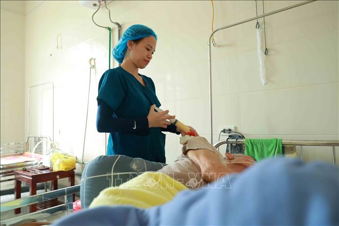 Đội ngũ điều dưỡng tận tình chăm sóc từng bữa ăn cho các cụ phải nuôi ăn qua ống xông. Ảnh: Hữu Quyết - TTXVN