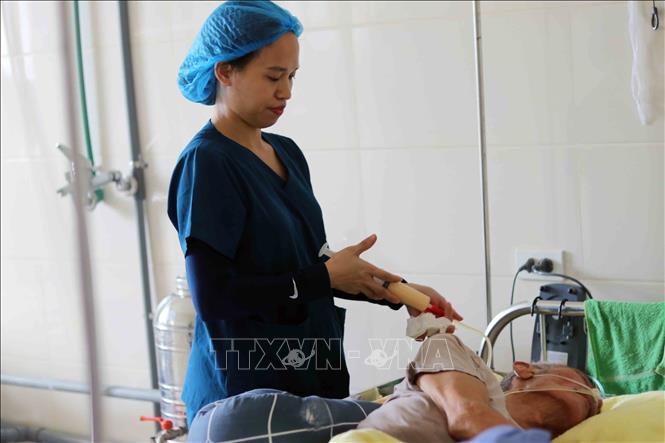 Công việc cho ăn qua ống xông được đội ngũ điều dưỡng thực hiện tỉ mỉ, bảo đảm an toàn cho người bệnh. Ảnh: Hữu Quyết - TTXVN